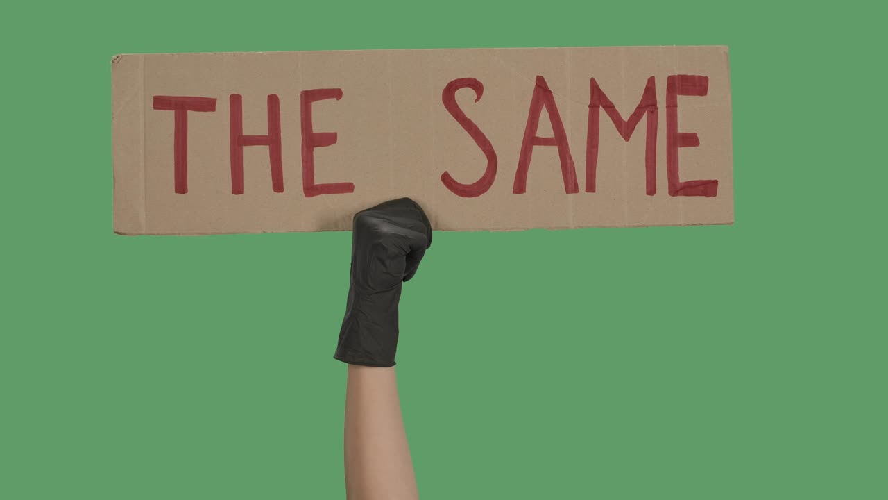 검은 장갑을 입은 손은 카드보드 포스터를 올리고, 평등과 통일 개념, 폭력의 다중성, 반 흑인 인종차별, 분리된 녹색 화면, 크로마 키, 클로즈업, 느린 동작.