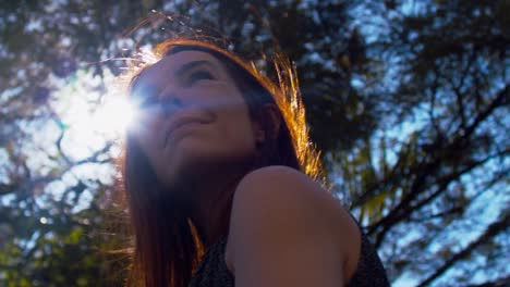 Attractive-woman-in-her-40s-waiting-in-a-park,-low-angle-with-lens-flare