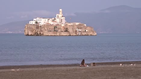 woman enjoying a warm day in the beach of al hoceima, morocco, with the spanish military island of alhucemas in front