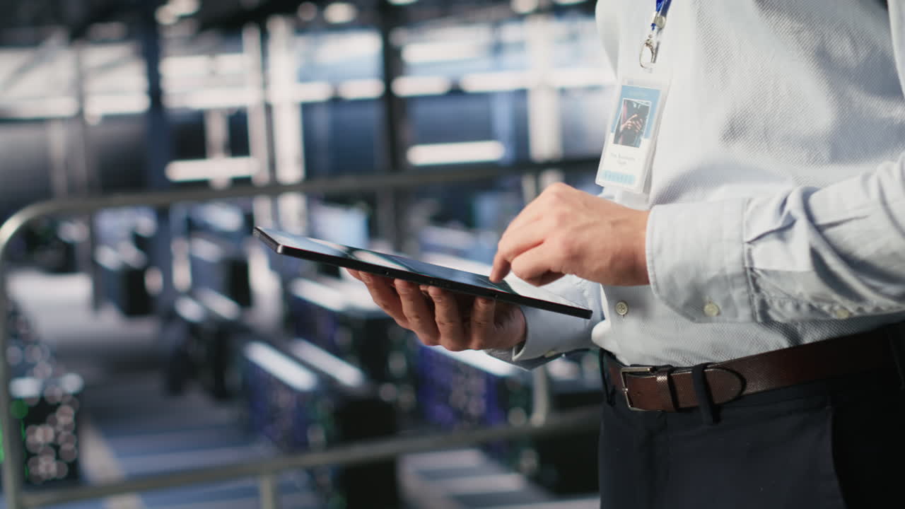 Close up of server room worker checking code on tablet next to colleague