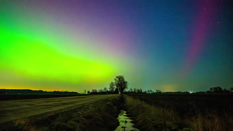 Timelapse-De-La-Vibrante-Aurora-Boreal-Brillando-Sobre-Una-Zanja-Y-Campos-Rurales