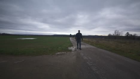 modern black swordsman warrior awaiting battle opponent in open field under grey sky, europe, 4k | muscular, intimidating, shadow, figure, blurry, dark clothes, powerful, puddle, slow walk, close move