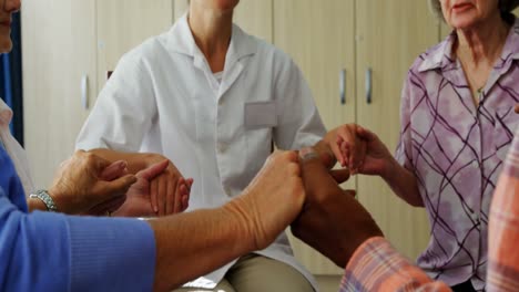ancianos y una doctora tomados de la mano mientras están sentados en sillas 4k