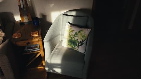 orbiting shot of a light blue chair with a pillow in the living room of a home half light by sunlight beaming through the window