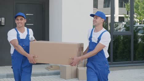 two young workers of removal company are loading boxes and furniture into a minibus