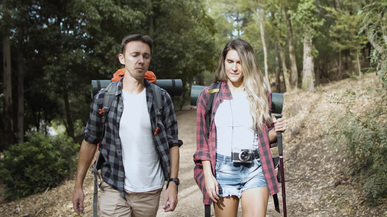 캠핑 배낭을 메고 말하고 걷는 두 명의 등산객