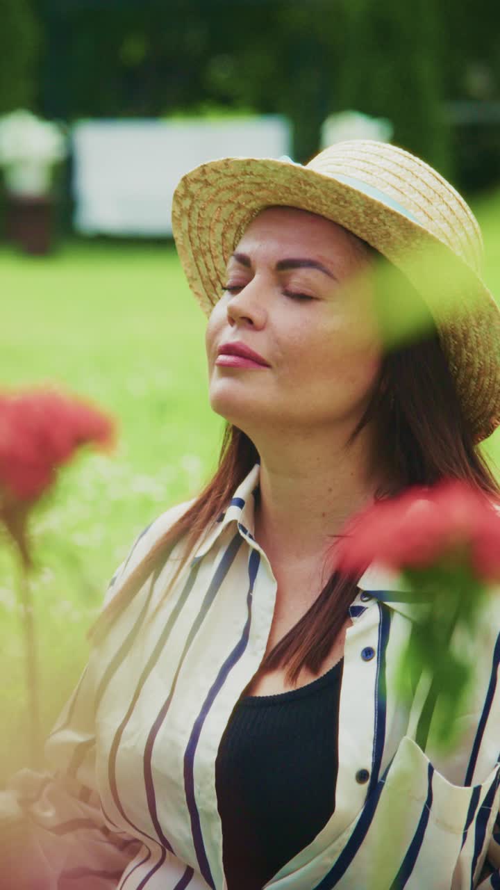 A Serene Moment in Nature: A Woman in a Straw Hat Enjoys the Peaceful Surroundings Surrounded by Vibrant Flowers and Lush Greenery