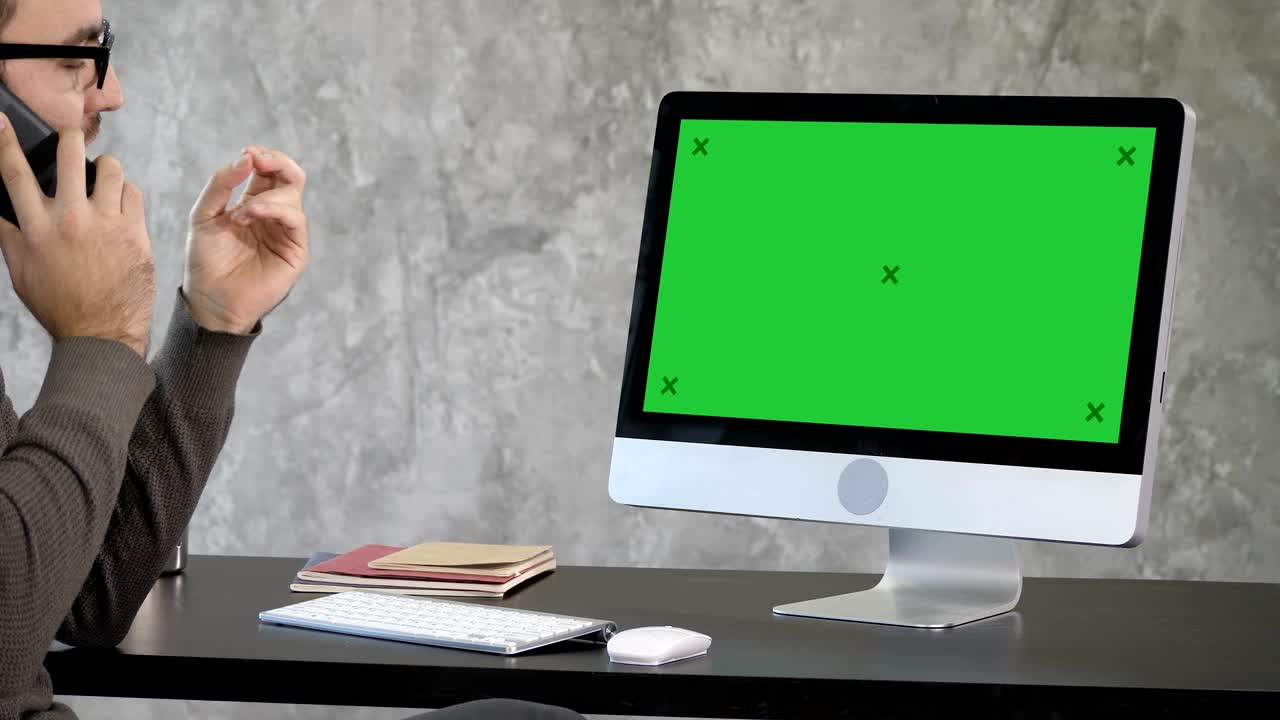 Business, deadline and technology concept - man with computer calling on smartphone and pointing to the monitor. Green Screen Mock-up Display