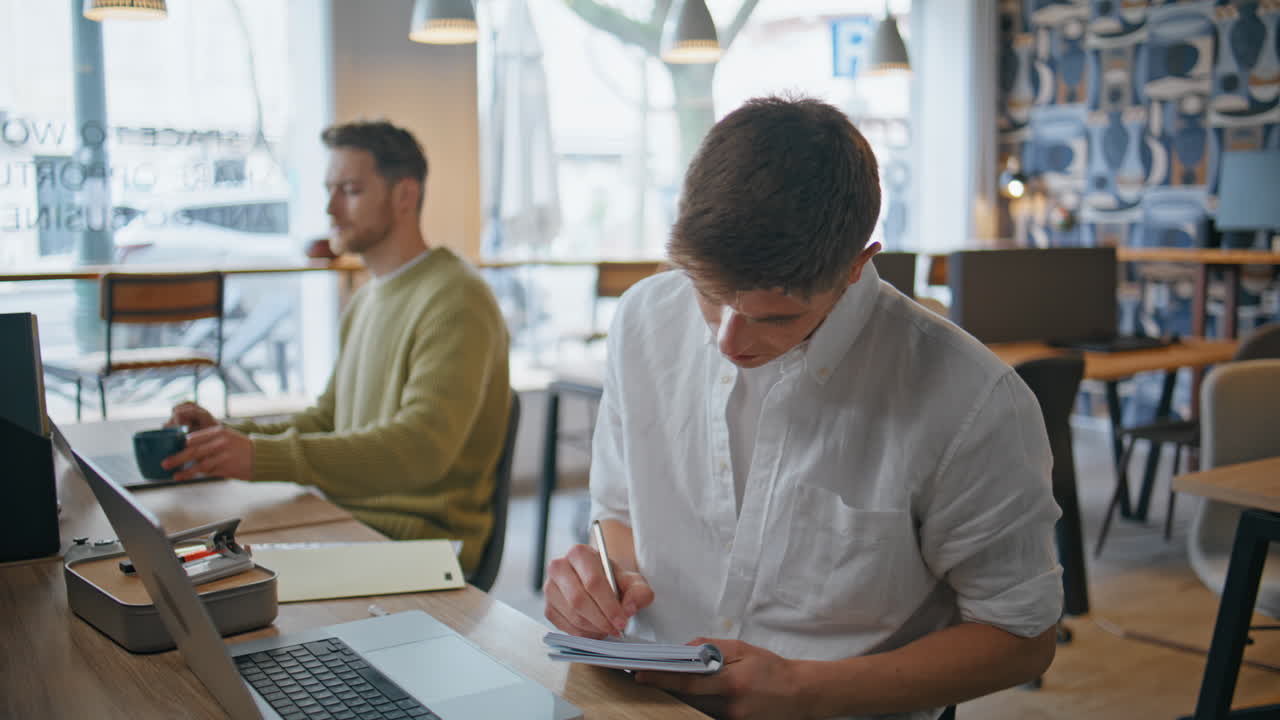Focused worker making notes in notebook sitting office closeup. Man writing