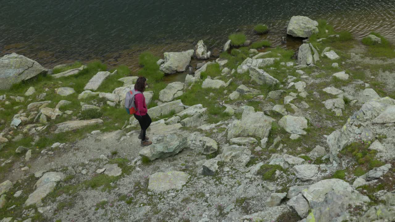 mujer caminando por un sendero rocoso junto al lago campagneda en valmalenco, italia