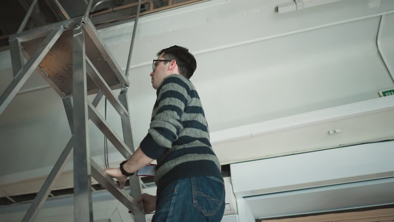 studio worker climbing ladder to adjust lighting equipment SL-200W, preparing for broadcast, organizing studio setup, adjusting light positioning, crew working with media equipment for production