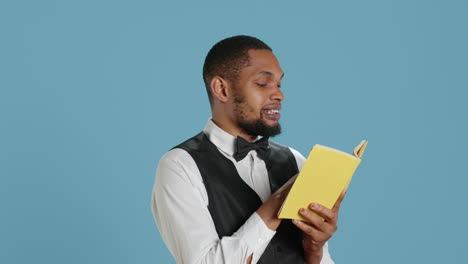 Young-doorman-hotelier-reading-a-book-on-his-work-break-in-studio