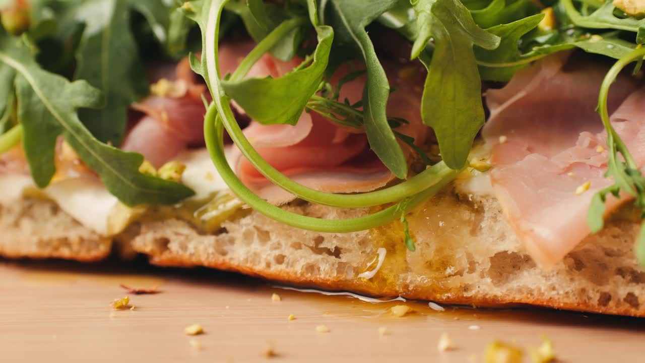 Mortadella ham sandwich, Traditional italian focaccia filled with thin pesto slices of mortadella, served by chef man in cafe restaurant. Macro of traditional italian spanish tapas antipasti.