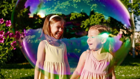 two young girls playing with a large colorful bubble in a sunny garden