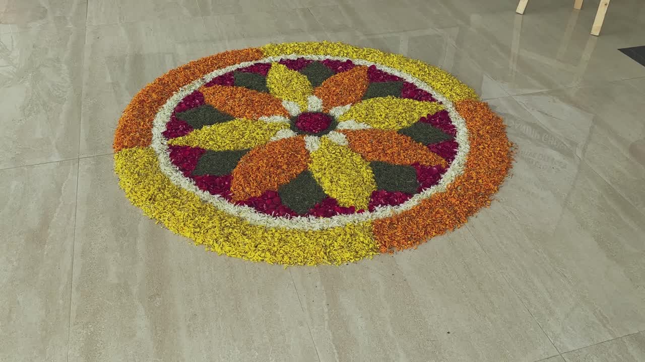 Camera circles around a vibrant flower-petal rangoli arranged in a colorful symmetrical pattern on a polished floor, highlighting festive detail and texture