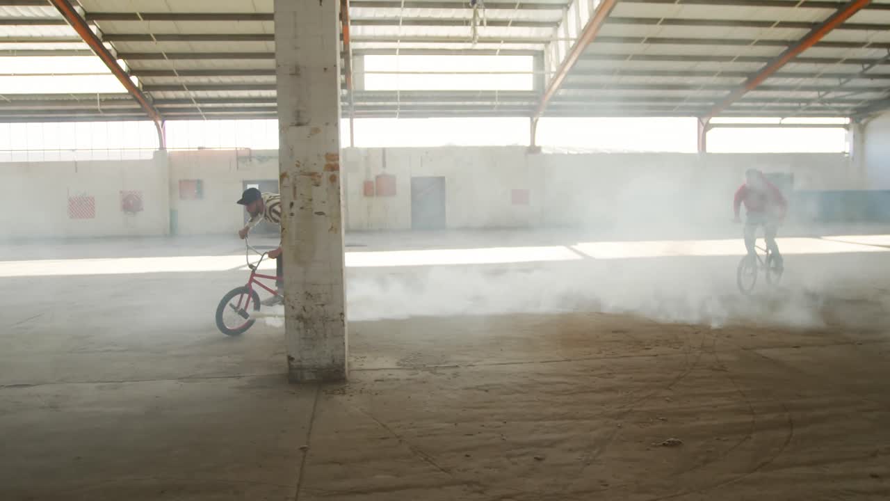 jinetes de bmx en un almacén vacío usando una granada de humo