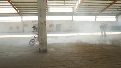 BMX-riders-in-an-empty-warehouse-using-smoke-grenade