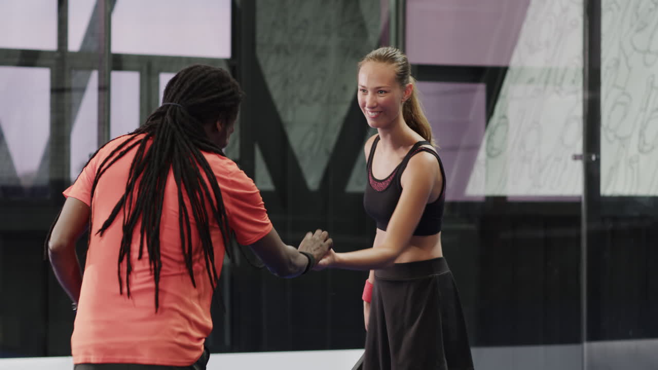 Man and woman playing padel tennis, enjoying friendly match on indoor court