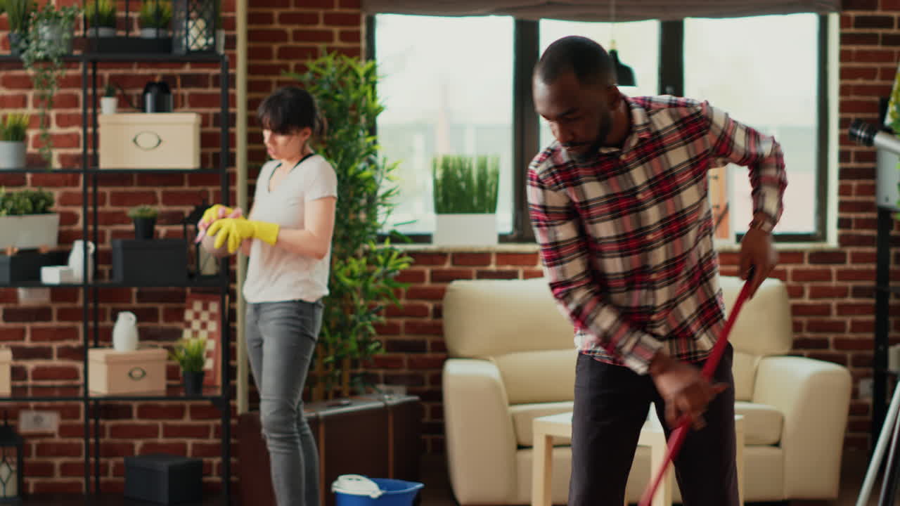 Diverse couple cleaning apartment with tools and appliances