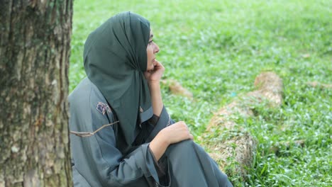 ,thoughtful muslim women sitting on park