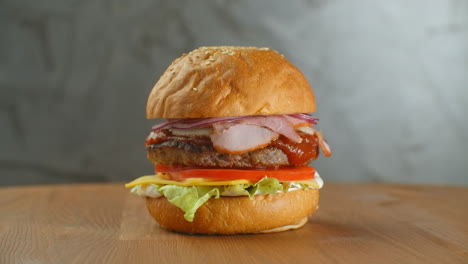 Yummy-fast-food-concept.-Fresh-homemade-grilled-burger-with-meat-patty-tomatoes-cucumber-lettuce-onion-and-sesame-seeds.-Unhealthy-lifestyle.-Food-background.