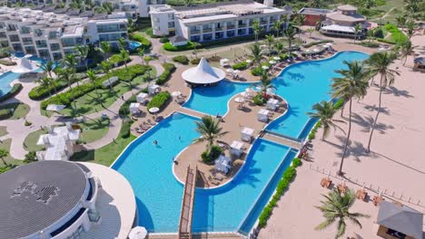 Aerial-top-down-shot-of-large-swimming-pool-area-with-tourist-relaxing-in-NICKELODEON-RESORT,-PUNTA-CANA