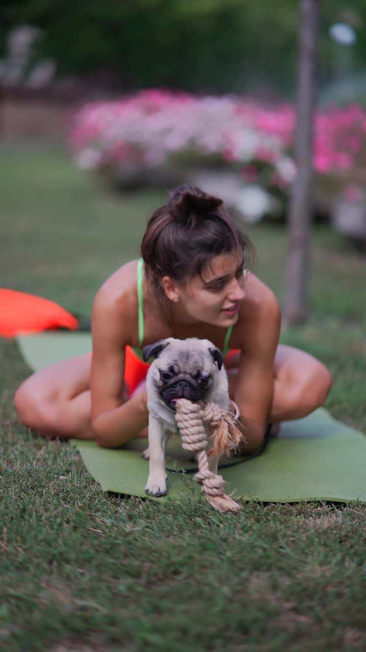공원 에서 그 강아지 와 함께 요가 를 연습 하는 여자