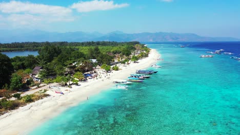 Weißer-Strand-Einer-Tropischen-Insel,-Umspült-Von-Einer-Türkisfarbenen-Lagune-Voller-Ausflugsboote,-Die-Darauf-Warten,-Dass-Touristen-An-Bord-Kommen-Und-Ihre-Reise-Um-Die-Inseln-Von-Bali-Beginnen