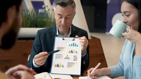 a work team discusses details of some data in a report in a coffee shop 1