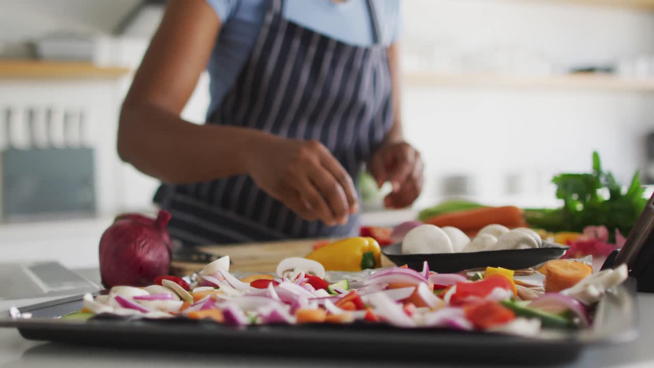 Happy african american woman preparing dinner in kitchen