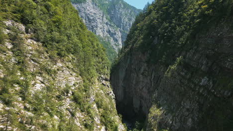 drone video flying under mountain road bridge panning up slowly to reveal deep chasm valley in the italian dolomites surrounded by mountains roads and cliffs