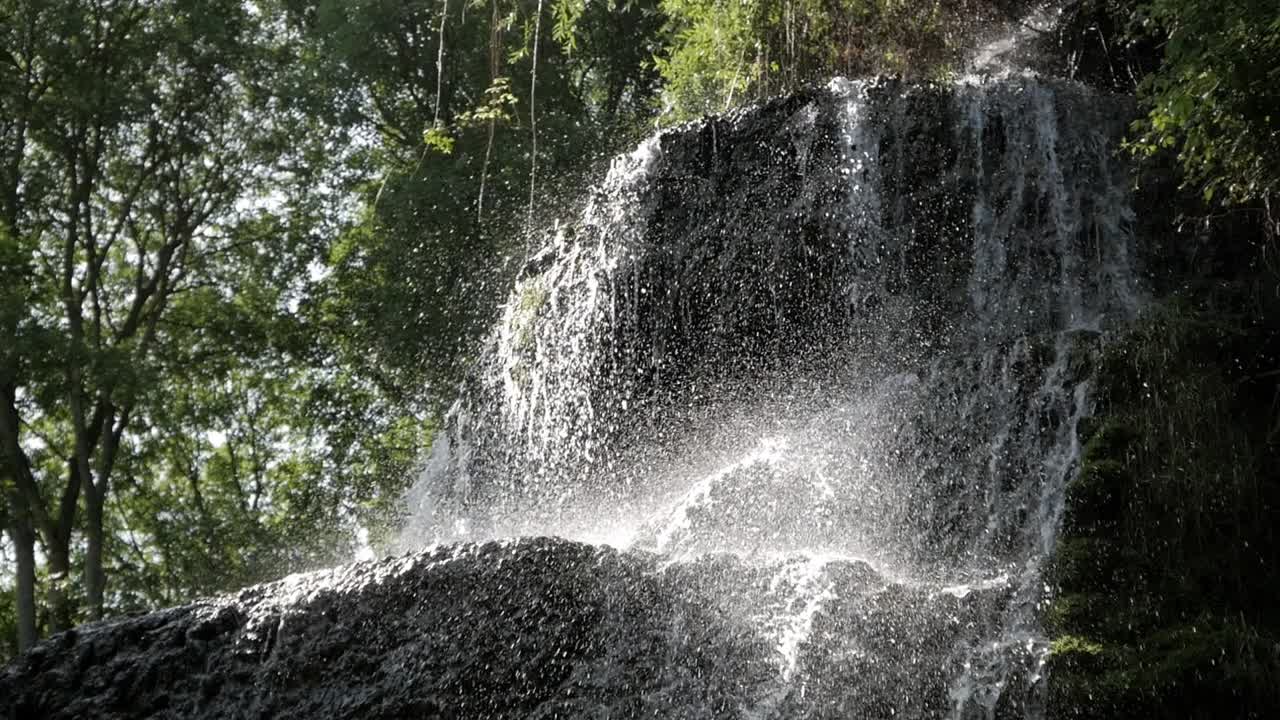 Beautiful waterfall cascade surrounded by trees. Rock formation overhang. Water splash on drop. Stunning sunlight shine on water drops. Monasterio de Piedra park, Zaragoza, Aragon, Spain