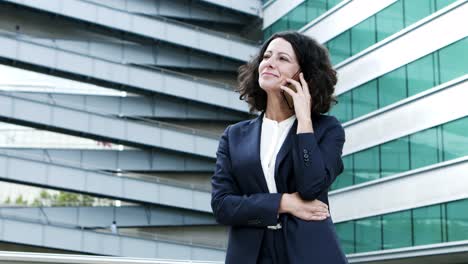 Cheerful-businesswoman-talking-by-cell-phone