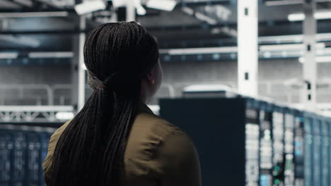 woman walking through data center server rows, checking equipment