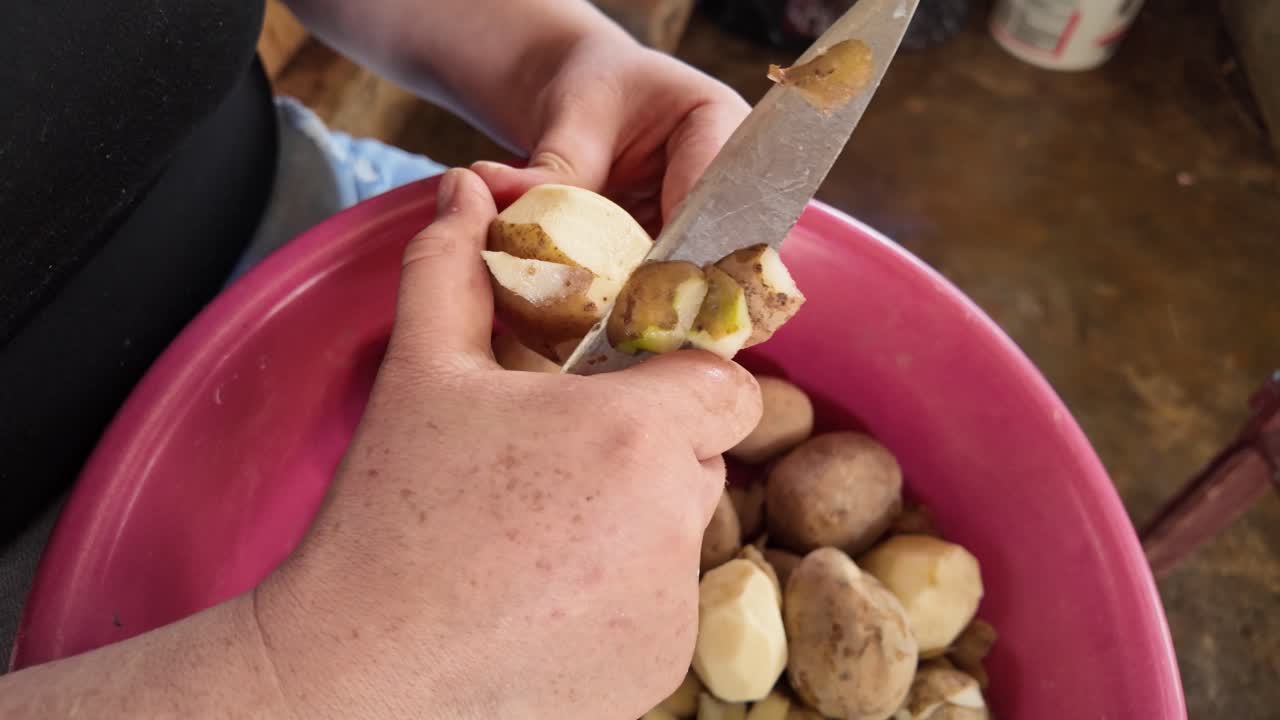 Woman peeling potatoes with a metal knife in the rural field. A shot highlighting manual labor and rural life, showcasing a connection to nature and the simplicity of countryside living