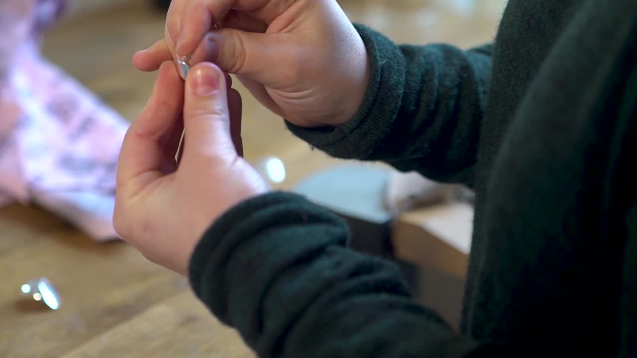 Close-up view of a woman's hands crafting silver jewelry