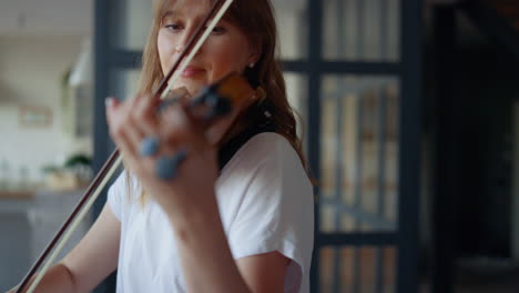 woman learning to play violin at home. romantic girl playing violin with bow