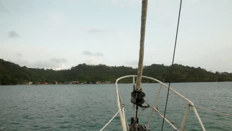 looking out from the sailboat’s bow, sapzurro bay stretches quiet and green beyond.