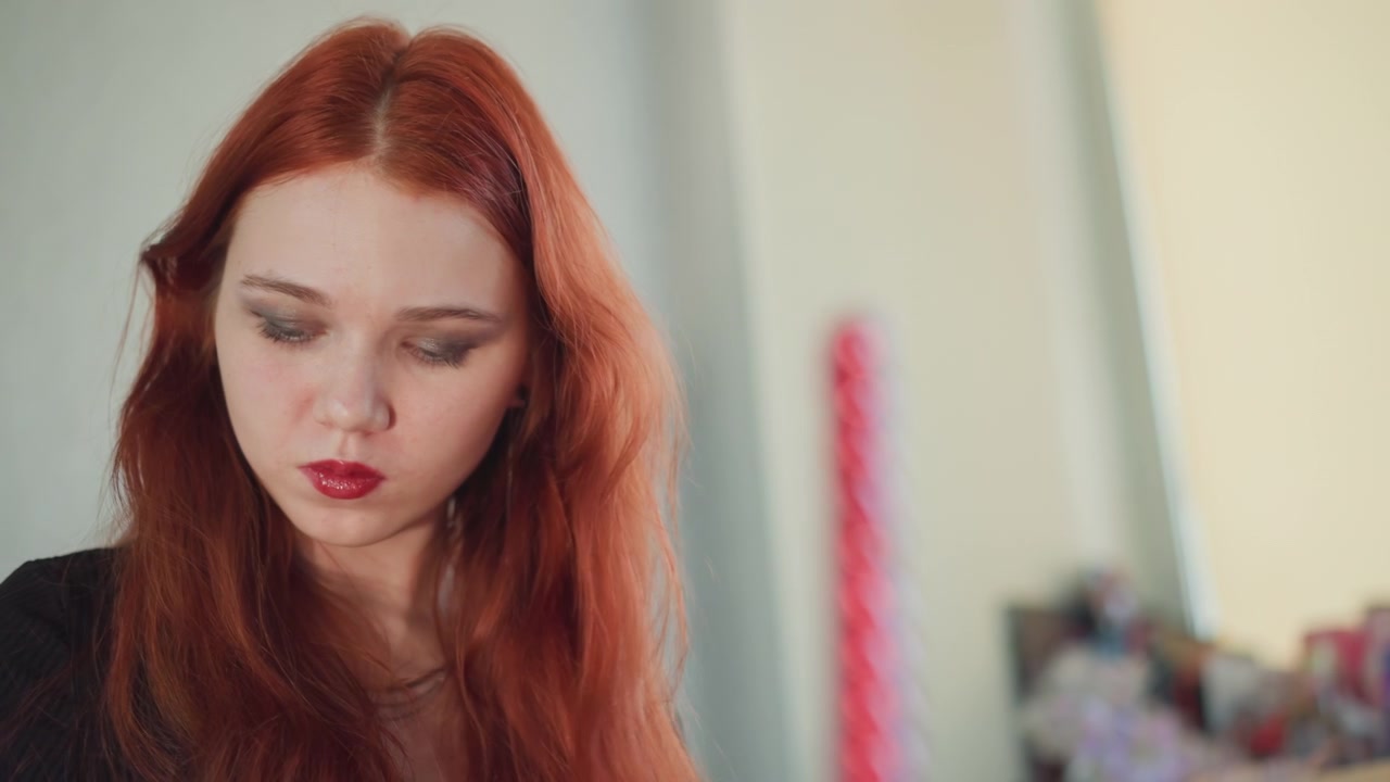 Medium shot caucasian redhead during focused scrying ritual, pink wand blurred in foreground, downward gaze and precise hand gestures, studio tabletop with props, soft natural lighting, intense