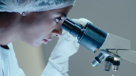 científica negra mirando en el microscopio de laboratorio