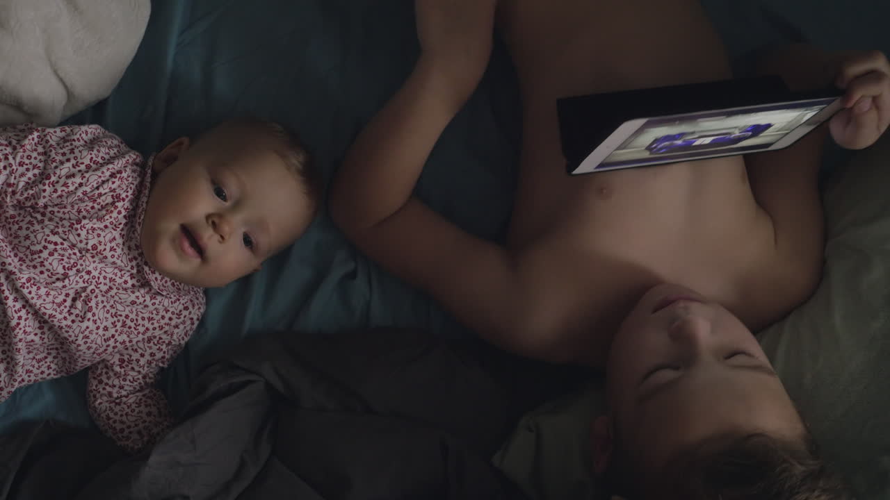 Brother on a tablet with younger baby sister