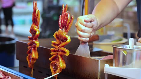 vendor grilling squid skewers at street food stall