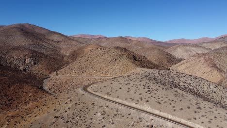 Unpaved-road-winds-its-way-through-endless-barren-hills-in-Chile