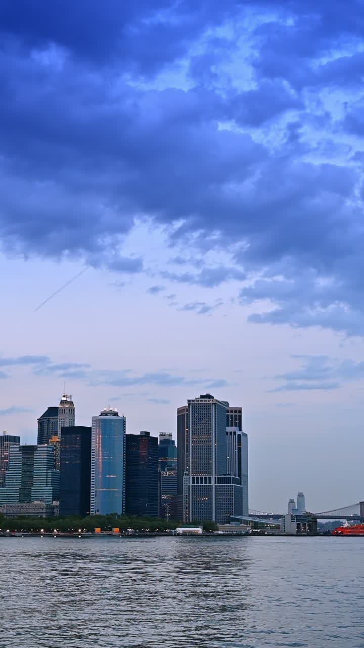 Dark blue clouds in the sky over New York skyline. View on the metropolis and bridge from the waterscape of the river. Vertical video