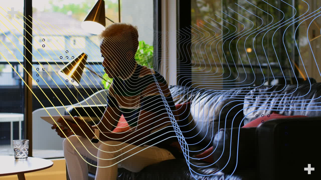 Animation of abstract colorful shapes over african american man using digital tablet at office