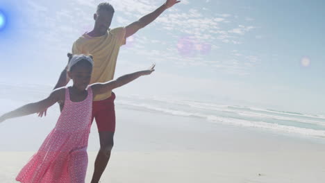 playing on sunny beach, father and child enjoying animation by ocean waves