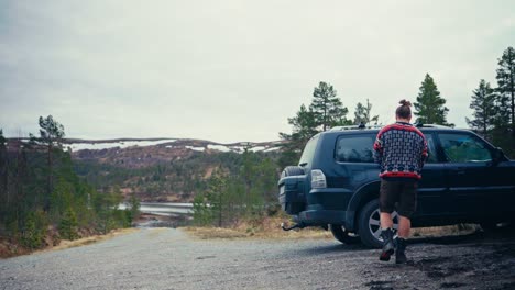 a man takes a backpack out of a car parked by the shores of reinsjøen in åfjord, trøndelag, norway - static shot