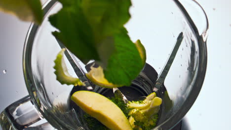 verduras frescas que caen en el cuenco de la licuadora para hacer una deliciosa bebida saludable de cerca.