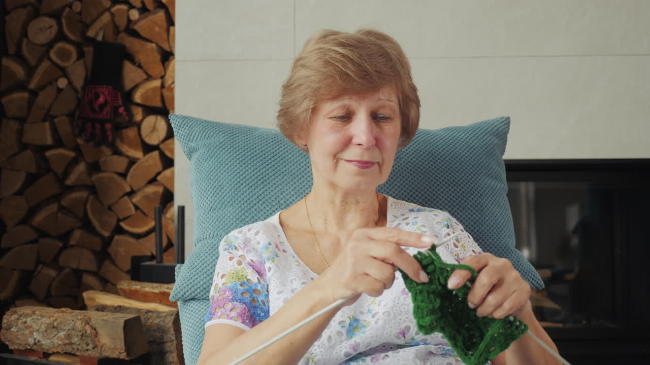 벽난로 에서 뜨개질하는 고위 여성