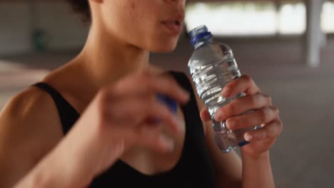 front view of young african american woman drinking water in the city 4k